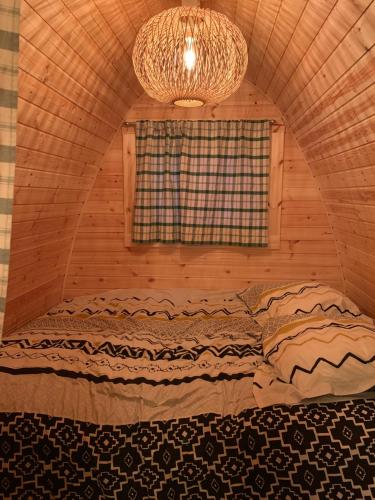 a bed in a room with a window and a chandelier at Le charmant Pod du Parolais in Beauvoisin