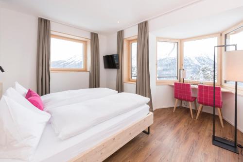 a bedroom with a bed and a table and chairs at Randolins Familienresort in St. Moritz