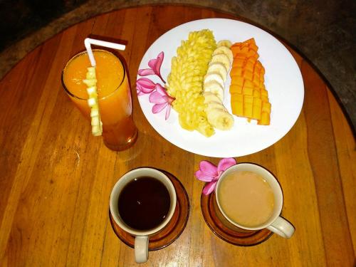 a table with a plate of food and two cups of coffee at Mengalung Bungalow in Kuta Lombok