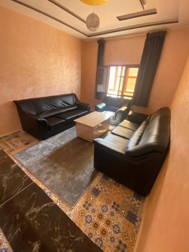 a living room with a leather couch and a table at Résidence AGDAL in Dakhla