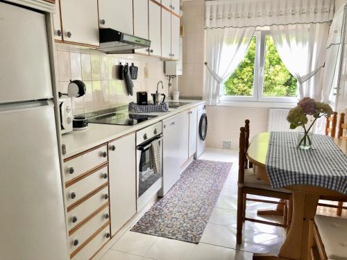 a kitchen with white appliances and a table and a window at Apartamento con vistas al mar en Primera Línea. in Muros