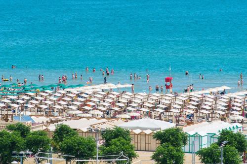 a beach with umbrellas and people in the water at Hotel Cristallo in Riccione