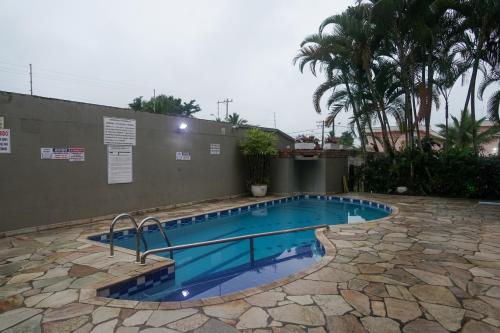a swimming pool with blue water in a yard at Apartamento Duplex a 100 metros da Praia de Boracéia in Bertioga