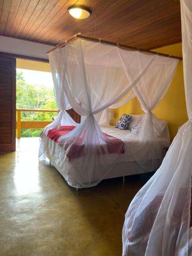 a bed with a canopy in a room at Pousada Arraial Colonial in Arraial d'Ajuda