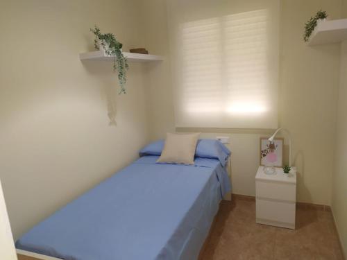 a small bedroom with a bed with blue sheets at Àtic Montsià - Àtic amb chill-out in Amposta