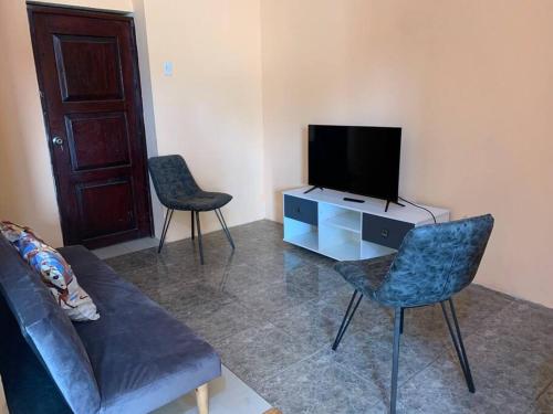 a living room with a couch and a tv and chairs at Acogedor Departamento Pequeño in La Libertad