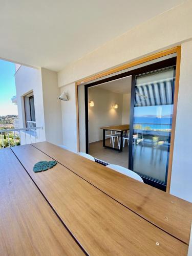 - une grande table en bois dans une chambre avec vue sur l'océan dans l'établissement Mimosas - Bel appartement avec une vue imprenable sur la baie, à Cavalaire-sur-Mer