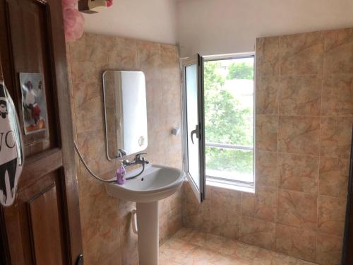baño con lavabo, espejo y ventana en Hakuna Matata Guest House, en Plovdiv