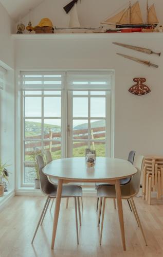 a white dining room with a table and chairs at Á Snætu - Serene Village Stay Surrounded by Nature in Sandavágur