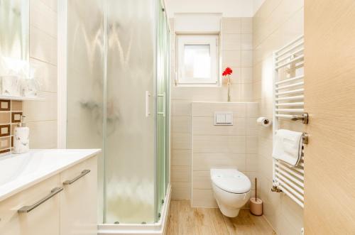 a white bathroom with a toilet and a shower at Apartments Hortensia in Pula