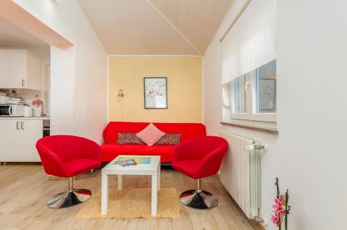 a living room with a red couch and two red chairs at Apartments Hortensia in Pula