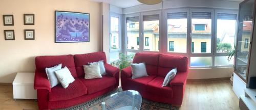 a living room with two red couches and windows at El trocito de mar in Luanco