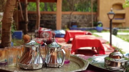 uma mesa com panelas de chá de prata e pratos sobre ela em Hôtel Restaurant Les Etoiles Du Toubkal em Imlil