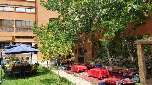 a garden with tables and chairs in front of a building at Hôtel Restaurant Les Etoiles Du Toubkal in Imlil