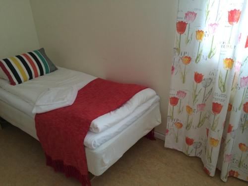 a small bedroom with a bed with a red blanket at STF Malmfältens Folkhögskola in Kiruna