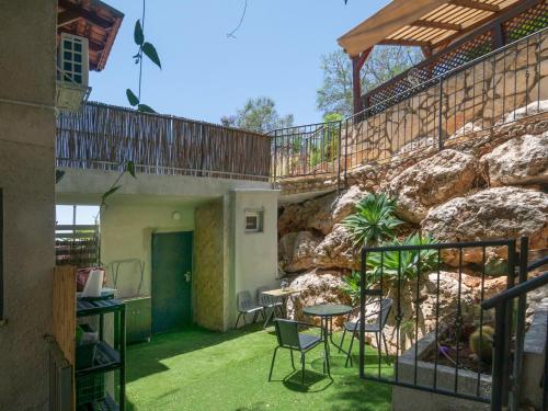 a patio with a table and chairs next to a rock wall at Panorama Golan נוף הגולן Дом в Галилее in Safed