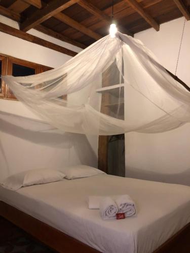 Una cama con sábanas blancas y toallas bajo un mosquitero. en Casa PALUM Prívate Room Prívate bathroom, en Palomino