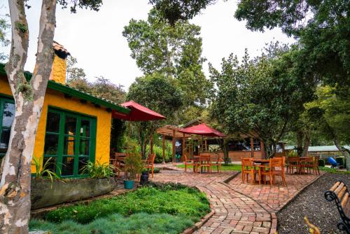 a patio with tables and chairs in a park at Estancia San Antonio in Guasca
