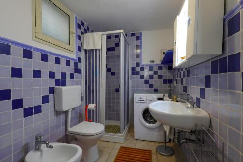 uma casa de banho em azulejos azuis com um WC e um lavatório em Grazioso Monolocale della Casa dell'Olivo em Salve