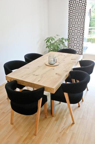 a wooden table with black chairs around it at Apartamenty Kotarz Sauna&Relaks in Brenna