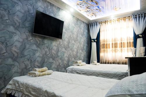 um quarto com duas camas e uma televisão na parede em Bonuluxhome em Samarkand