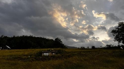 a cloudy sky above a field with a house at Tara Place - Camp Rabrenovic in Mojkovac
