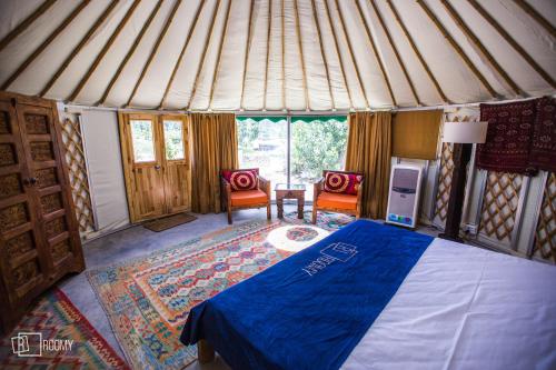 a bedroom with a bed and two chairs in a yurt at Roomy Yurts, Gulmit Hunza in Gulmit