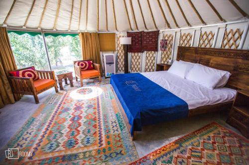 a bedroom with a bed and two chairs and a rug at Roomy Yurts, Gulmit Hunza in Gulmit