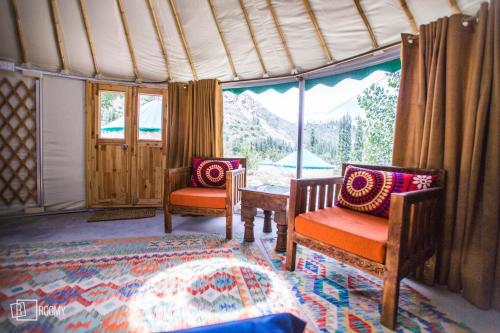 a room with two chairs and a table and a window at Roomy Yurts, Gulmit Hunza in Gulmit