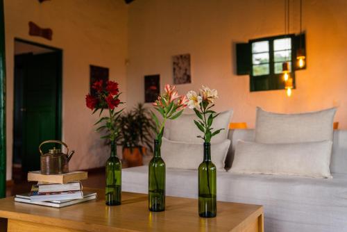three green bottles sitting on a table with flowers at Estancia San Antonio in Guasca