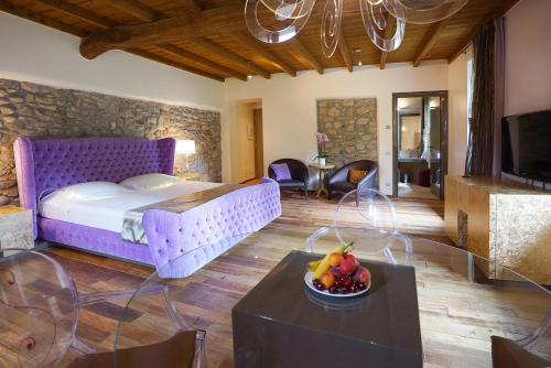 um quarto com uma cama roxa e uma mesa com uma tigela de fruta em Il Portico - 1711 Luxury Guest House em Arlate
