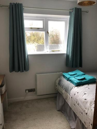 - une chambre avec un lit et une fenêtre avec des rideaux bleus dans l'établissement Chapel View Cottage, à Beaminster