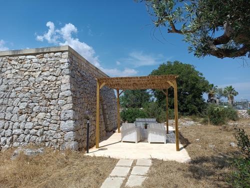 a stone wall with a table and a pavilion at Liama sull'Aia in Marina di Pescoluse