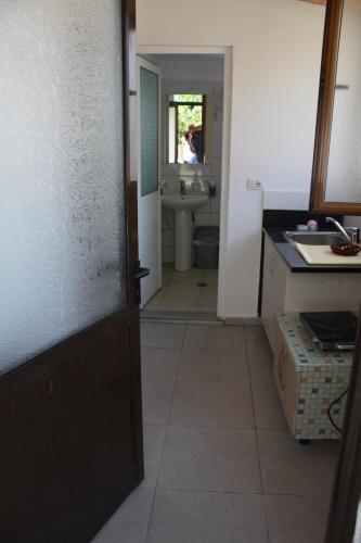 a kitchen with a door leading to a bathroom with a sink at Guesthouse Benardo in Sarandë