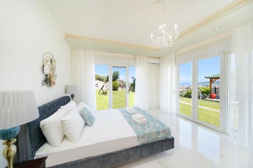 a white bedroom with a large bed and windows at Villa Valia Calda in Limenas