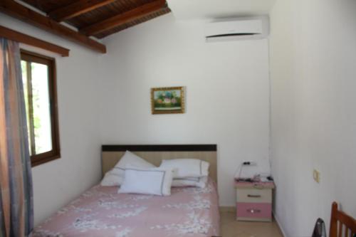 a bedroom with a bed with white walls and a window at Guesthouse Benardo in Sarandë