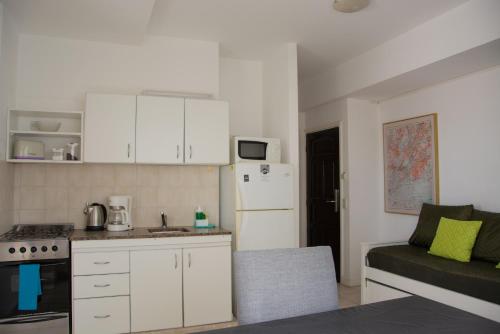una cocina con armarios blancos y un sofá en una habitación en Alma Departamentos de Mar en Ostende