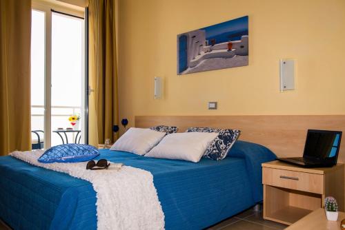 a hotel room with a bed with a blue comforter at Hotel Caggiari in Senigallia