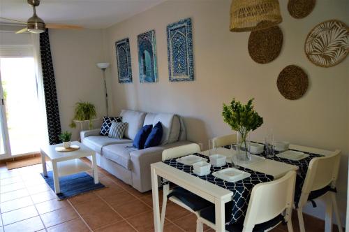 a living room with a table and a couch at Bonito apartamento con jardín privado en Novo in Novo Sancti Petri