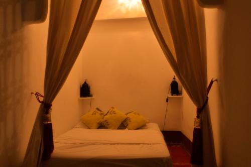 1 dormitorio con cama con almohadas y cortinas amarillas en Riad Dar Mchicha by phoenix, en Marrakech