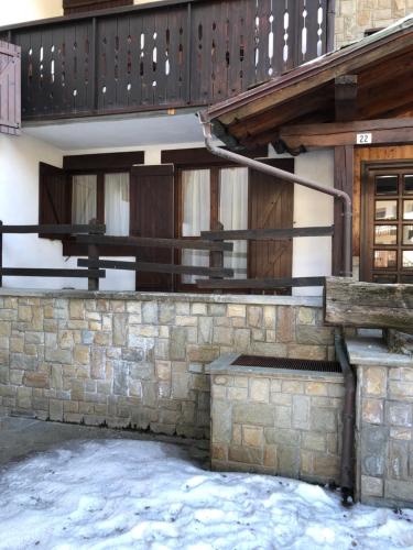 a building with a stone wall and a balcony at Accogliente appartamento in centro Champoluc in Champoluc