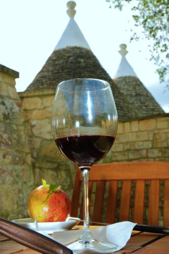 a glass of wine sitting on a table with an apple at Trulli Vulés in Ostuni