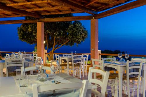 a table with white chairs and wine glasses at Hotel Trinità dei Corsari in Torre Dei Corsari