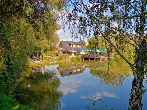 a reflection of a house in a lake with a dock at Cyklistika+rybaření+památky in Rebešovice