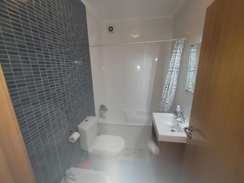 La salle de bains est pourvue de toilettes blanches et d'un lavabo. dans l'établissement Alojamento Valverde, à Nazaré