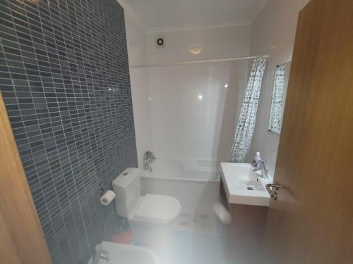 a bathroom with a white toilet and a sink at Alojamento Valverde in Nazaré