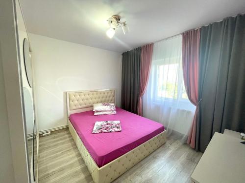 a small bedroom with a pink bed and a window at Residence RMZ in Mangalia