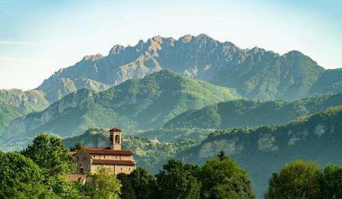 a building with a clock tower in front of a mountain at Il Portico - 1711 Luxury Guest House in Arlate