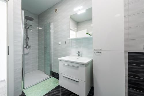 y baño blanco con lavabo y ducha. en Village apartments Mimi, en Pridvorje