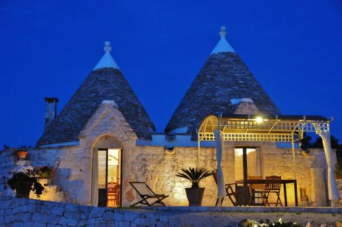 a stone house with a gazebo at night at Trulli Vulés in Ostuni